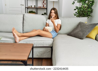 Adorable girl watching movie sitting on sofa at home - Shutterstock ID 2232414435