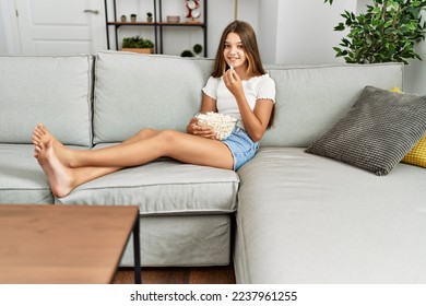 Adorable girl watching movie sitting on sofa at home - Shutterstock ID 2237961255