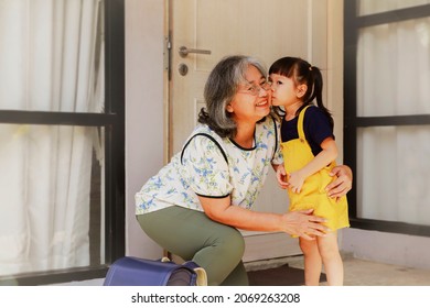 Adorable granddaughter showing love, bonding, warm heart, standing and kissing Grandma's cheek in front of the door before going to kindergarten.