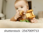 Adorable happy baby boy playing with wooden toys on bed. Childhood. Portrait of cute emotional child infant teething with eco toys