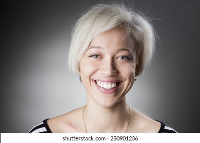 Adorable Happy Blonde With Short Hair Looking Into The Camera And Smiling A Big Smile With Healthy Teeth