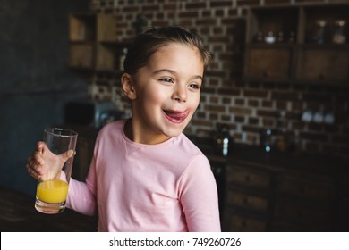 Adorable Happy Child Drinking Orange Juice And Licking Lips