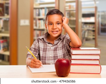 Adorable Hispanic Boy With Books, Apple, Pencil And Paper Studying At The Library.