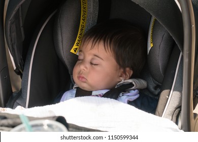 Adorable Infant Baby Girl Sleeping In Protective Car Seat. Harness Seat Into Motor Vehicle Rear Facing For Child Safety In Moving Automobile With Shoulder Lap And Chest Strap. Movement Rock To Sleep