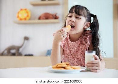 adorable kid eating cookie and milk on the table