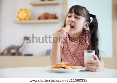 adorable kid eating cookie and milk on the table
