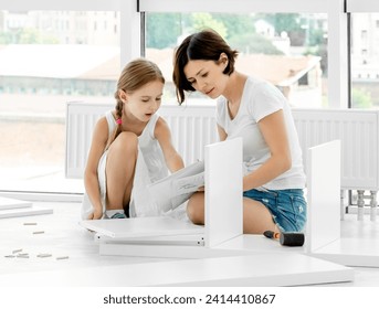 Adorable kid girl helping mother in installing brand new bookshelf