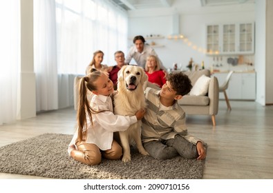 Adorable kids hugging cute golden retriever dog, sitting on floor together, their parents and grandparents on background. Big multi generation family spending bonding times at home - Powered by Shutterstock