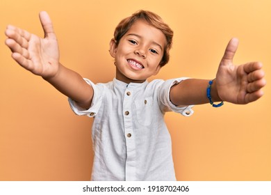 Adorable latin kid wearing casual clothes looking at the camera smiling with open arms for hug. cheerful expression embracing happiness. 