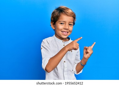 Adorable Latin Kid Wearing Casual Clothes Smiling And Looking At The Camera Pointing With Two Hands And Fingers To The Side. 