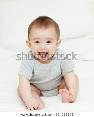 Der kleine Junge lächelt im Bett in seinem eigenen Zimmer.