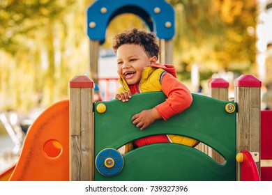 Adorable little 1-2 year old toddler boy having fun on playground, child wearing orange hoody jacket and yellow vest  - Powered by Shutterstock