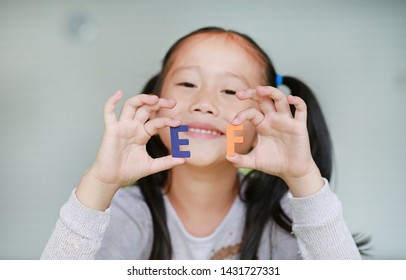 Adorable Little Asian Child Girl Holding Alphabet EF (Executive Functions) Text On Her Face. Education And Development Concept.