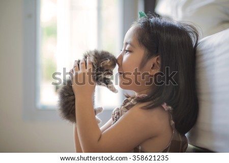 Adorable little asian girl kissing her kitten