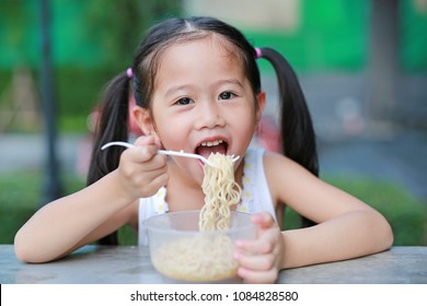 Adorable Little Asian Kid Girl Eating Instant Noodles In The Morning At The Garden.