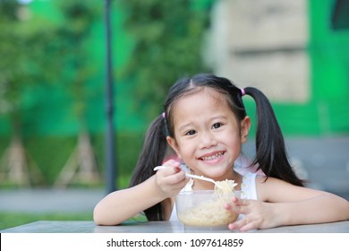 Adorable Little Asian Kid Girl Eating Instant Noodles In The Morning At The Garden.