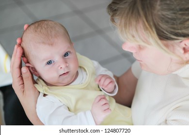 Adorable little baby boy on arm of happy young mother indoor