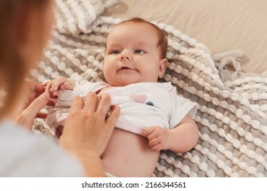 Adorable little baby girl looking at mother dressing her in white t-shirt - Powered by Shutterstock