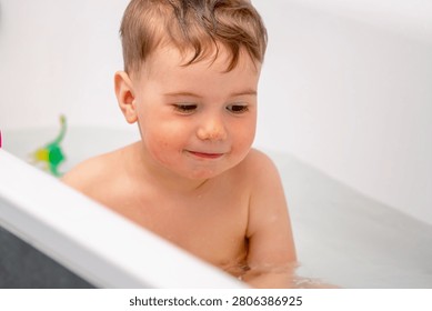 Adorable little boy developing coordination through water play in the bathtub.