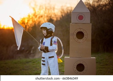 Adorable little boy, dressed as astronaut, playing in the park with rocket and flag, dreaming about becoming an astronaut