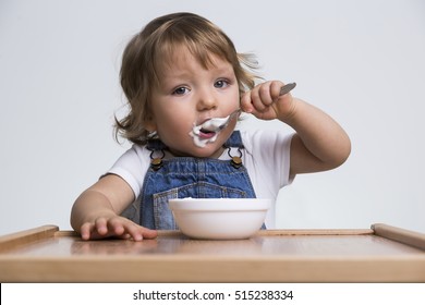 Adorable little boy eating his porridge with a small spoon. Concept of good eating habits