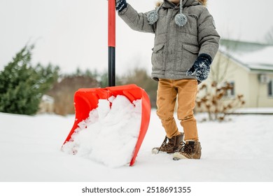 Adorable little boy helping to shovel snow in a backyard on winter day. Cute child wearing warm clothes playing in a snow. Winter activities for family with kids. - Powered by Shutterstock