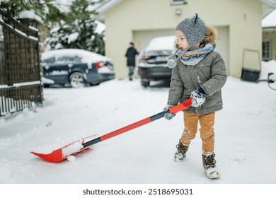 Adorable little boy helping to shovel snow in a backyard on winter day. Cute child wearing warm clothes playing in a snow. Winter activities for family with kids. - Powered by Shutterstock