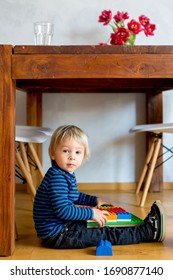 Adorable Little Boy Playing With Colorful Plastic Construction Blocks At Home, Sitting On The Floor Under The Table. Creative Games For Kids