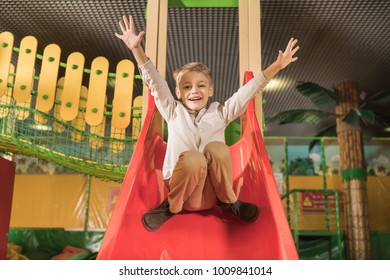 Adorable Little Boy Smiling At Camera While Playing On Slide In Game Center