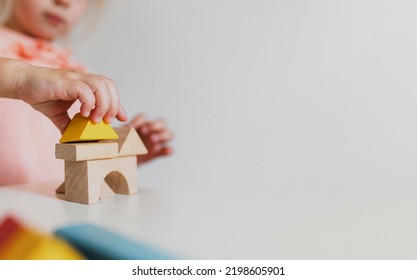 Adorable little child girl of preschooler age playing wooden building blocks at home or kindergarten. Toddler kid is stacking a tower from colourful cube toys on the table. Kids Play Room. Banner size - Shutterstock ID 2198605901