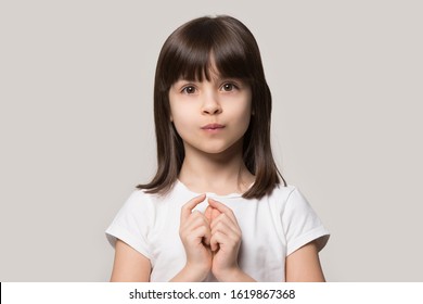 Adorable Little Curious Girl Hesitating Asking Questions. Shy Brown-haired Cutie Close Up Head Shot Portrait. 6 Years Old Unconfident Child Looking At Camera, Isolated On Grey Studio Background.