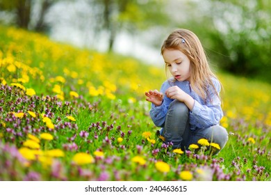 Adorable little girl in blooming dandelion flowers