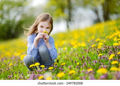 Adorable little girl in blooming dandelion flowers