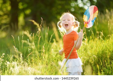 Adorable little girl catching butterflies and bugs with her scoop-net. Child exploring nature on sunny summer day. Family leisure with kids at summer. - Powered by Shutterstock