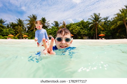 여름방학 동안, 사랑스러운 어린 소녀와 귀여운 소년이 열대 바닷물에 물을 튀기고 있다