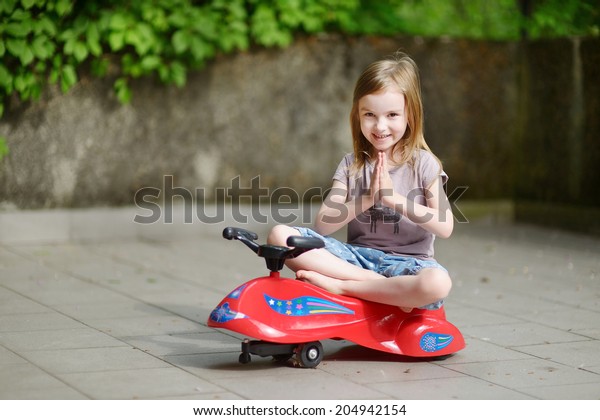 little girl driving toy car