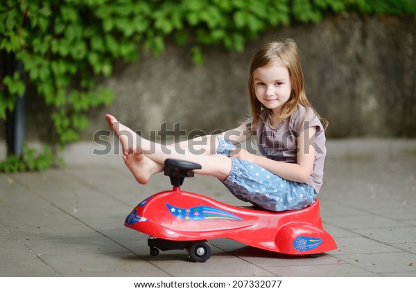 little girl driving toy car