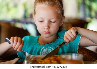 Adorable Little Girl Eating Breakfast In Restaurant