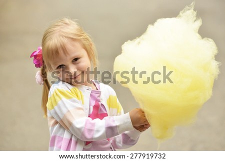 Adorable little girl eating candy-floss