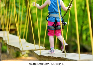 Adorable Little Girl Enjoying Her Time In Climbing Adventure Park On Warm And Sunny Summer Day. Summer Activities For Young Kids. Child Having Fun On School Vacations. 