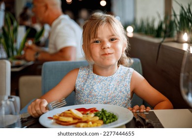 Adorable little girl having breakfast at resort restaurant. Happy preschool child eating healthy food, vegetables and eggs in the morning. - Powered by Shutterstock