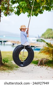 Adorable little girl having fun on tire swing on summer day