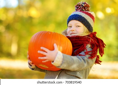 Adorable little girl having fun on a pumpkin patch on beautiful autumn day outdoors. Happy child playing in autumn park. Kid gathering yellow fall foliage. Autumn activities for children. - Powered by Shutterstock