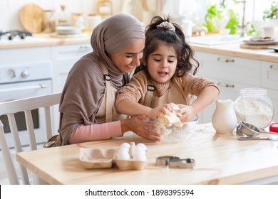 Adorable Little Girl And Her Muslim Mom Cooking In Kitchen, Kneading Dough For Cookies Together. Happy Islamic Mother In Hijab And Her Female Kid Having Fun At Home, Enjoying Making Homemade Pastry - Powered by Shutterstock