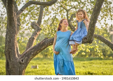 Adorable Little Girl And Her Pregnant Mom Enjoying Her Time In Park On Warm And Sunny Summer Day. Child Having Fun On School Vacations.