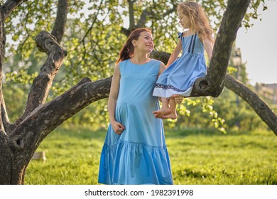 Adorable Little Girl And Her Pregnant Mom Enjoying Her Time In Park On Warm And Sunny Summer Day. Child Having Fun On School Vacations.