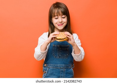 Adorable little girl with her tongue out and craving a cheeseburger she is about to eat in a studio - Shutterstock ID 2142082743
