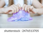 Adorable little girl holding a slime toy, a popular homemade toy all over the world. A child plays with slime and stretches it.