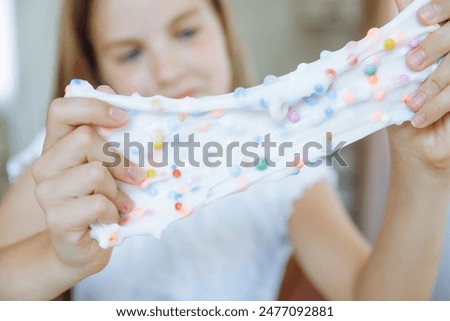 Adorable little girl holding a slime toy, a popular homemade toy all over the world. A child plays with slime and stretches it.