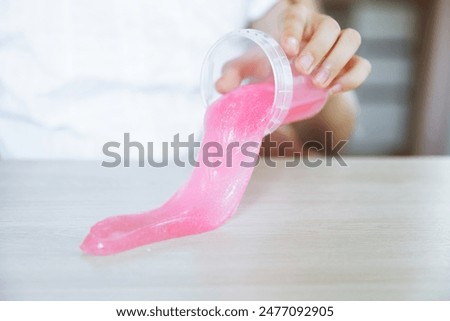 Adorable little girl holding a slime toy, a popular homemade toy all over the world. A child plays with slime and stretches it.